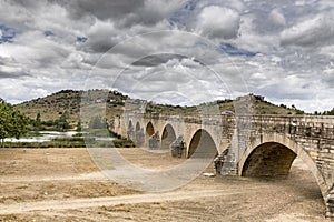 Felipe IV bridge Puente de los Austrias over Guadiana river in MedellÃ­n town on a cloudy day, Badajoz