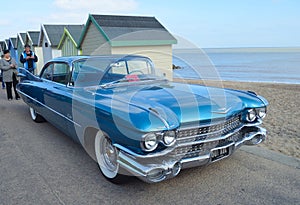 Classic Blue Cadillac Automobile parked on seafront promenade.