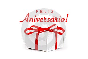 Feliz Aniversario! in Portuguese language: Happy Birthday! text message and white cardboard gift box with decorative red ribbon photo