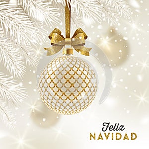 Feliz navidad - Christmas greetings in Spanish - patterned golden bauble with glitter gold bow hanging on a christmas tree.