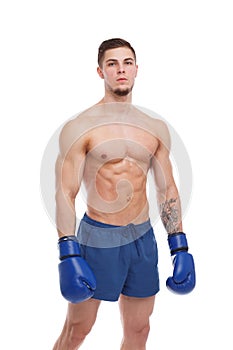 A fellow boxer, with a muscular torso, in shorts and boxing gloves, stands with a serious look.