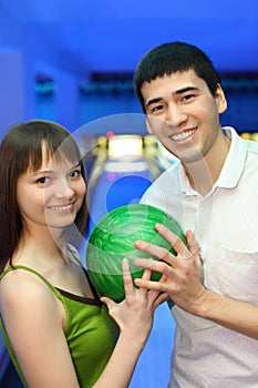 Fellow and girl turned to each other and hold ball