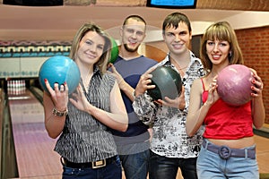Fellows and girls stand hold balls for bowling