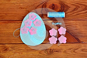 Felt Easter egg with flowers on a brown wooden background. Sew the flowers to the felt egg. Sewing set