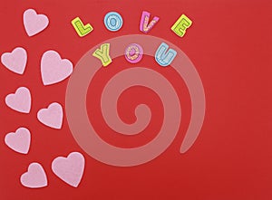 Felt hearts on red background with Love you text photo