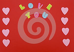 Felt hearts on red background with Love you text photo