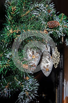 Felt icicles with snowflakes and buttons on green pine branches with snow and a pine cone.