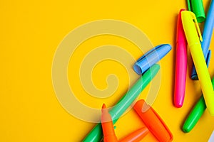 Felt-tip pens on a yellow background with copy space, set of new bright plastic opened colored felt pens near the caps