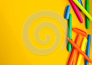 Felt-tip pens on a yellow background with copy space, set of new bright plastic opened colored felt pens near the caps