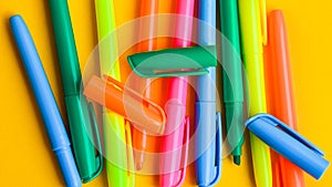 Felt-tip pens on a yellow background with copy space, set of new bright plastic opened colored felt pens near the caps