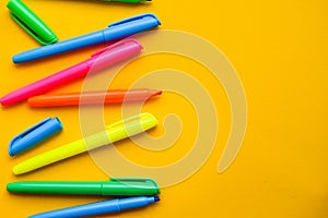 Felt-tip pens on a yellow background with copy space, set of new bright plastic opened colored felt pens near the caps