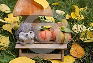 Felted hedgehog on a plywood bench in nature under a mushroom