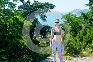 Female 25-30, on the hill wearing sunglasses, bra and pants.