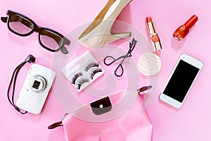 Female accessories and shoes with cosmetic set on pink background