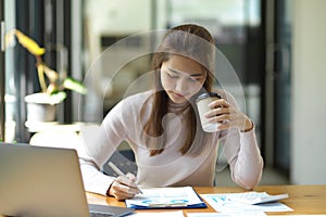 Female accountant checking economic paper report at workplace