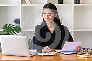Accountant checking financial reports and working with computer laptop in office.