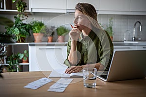 Female accountant freelancer working at home analysing company budget, counting income and expenses