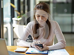 Female accountant using a smartphone at her office desk