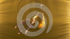 A female acrobat rotates in an air hoop and performs tricks. Exciting acrobatic show in a dark studio with yellow stage