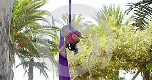 Female acrobat working outdoors on silk ribbons