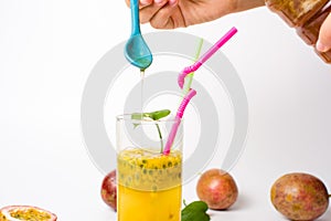 Female adding honey in passion fruit juice