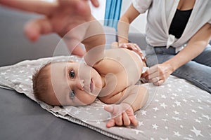 Woman putting diaper on baby, reaching out to camera