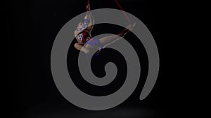 Female aerial gymnast performing on a red silk in a black background. Exciting acrobatic show. Slow motion. 139