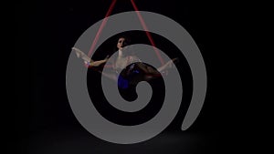 Female aerial gymnast performing on a red silk in a black background. Exciting acrobatic show. Slow motion. 145