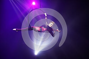 Female aerialist make flexible split on aerial hoop in air