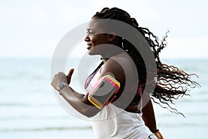 Female african runner jogging during outdoor workout on beach under rain