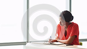 Female African writer busy working while seated next to a window