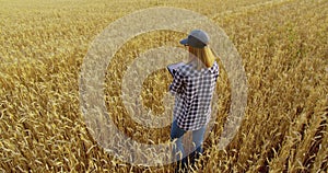 Female agronomist farmer with tablet in golden wheat field