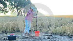 Female agronomy specialist performing soil sampling at sunrise