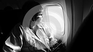female airplane passanger seeing out of airplane cabin window, black and white high contrast picture style, highlight on woman