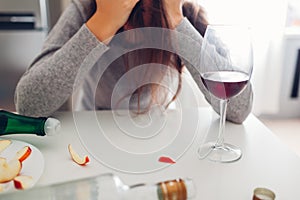 Female alcohol addiction. Young woman woke up on kitchen after party surrounded with wine bottles. Hangover