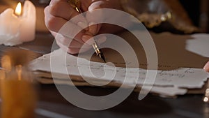 Female in antique outfit writes with feather pen. Close up shot of woman writing a letter with vintage quill on old