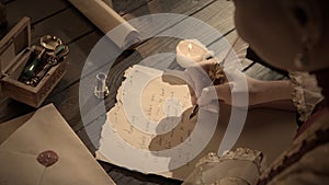 Female in antique outfit writes with feather pen. Shot of woman writing a letter with vintage quill feather pen on old