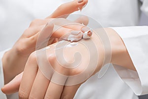 Female apply white moisturizer on her palm close up. Female applying hands care lotion. Body care lotion on a female palm