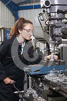 Female Apprentice Engineer Working On Drill In Factory