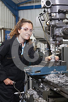 Female Apprentice Engineer Working On Drill In Factory