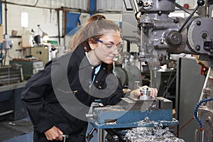 Female Apprentice Engineer Working On Drill In Factory