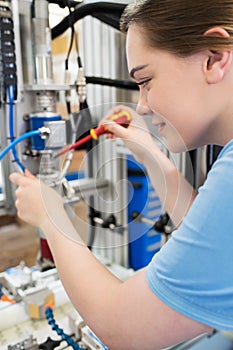 Female Apprentice Engineer Working On Machine In Factory