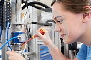 Female Apprentice Engineer Working On Machine In Factory