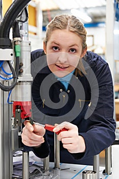 Female Apprentice Engineer Working On Machine In Factory