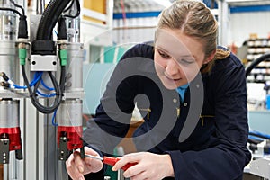 Female Apprentice Engineer Working On Machine In Factory