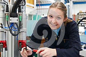 Female Apprentice Engineer Working On Machinery In Factory