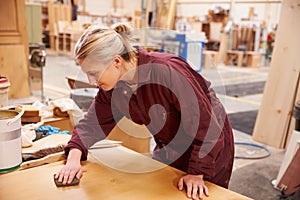 Female Apprentice Finishing Wood In Carpentry Workshop