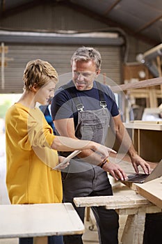 Female Apprentice Learning Skills From Mature Male Carpenter In Furniture Workshop