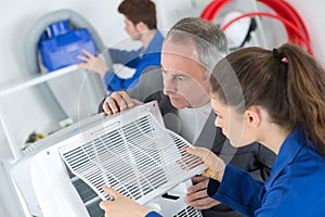 Female apprentice learning to repair industrial air conditioning compressor