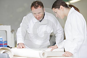 female apprentice learning wallpapering techniques